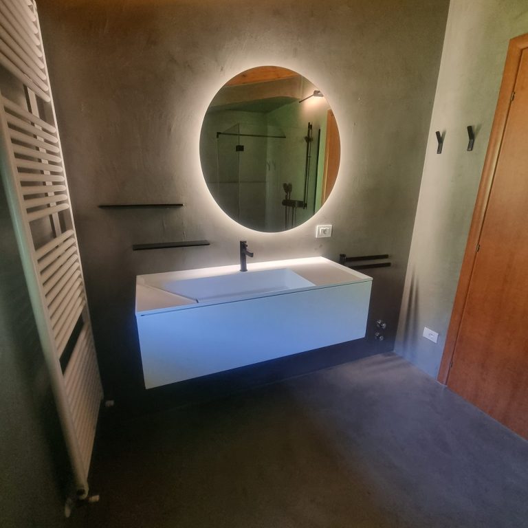Waschtisch nach der Sanierung Modernisiertes Badezimmer mit beleuchtetem Rundspiegel und Mikrozemet am Gardasee