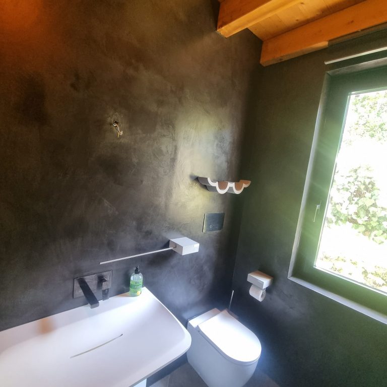 Gäste-WC nach der Modernisierung Modernisiertes Gäste-WC mit Mikrozement und schwarzen Armaturen am Gardasee